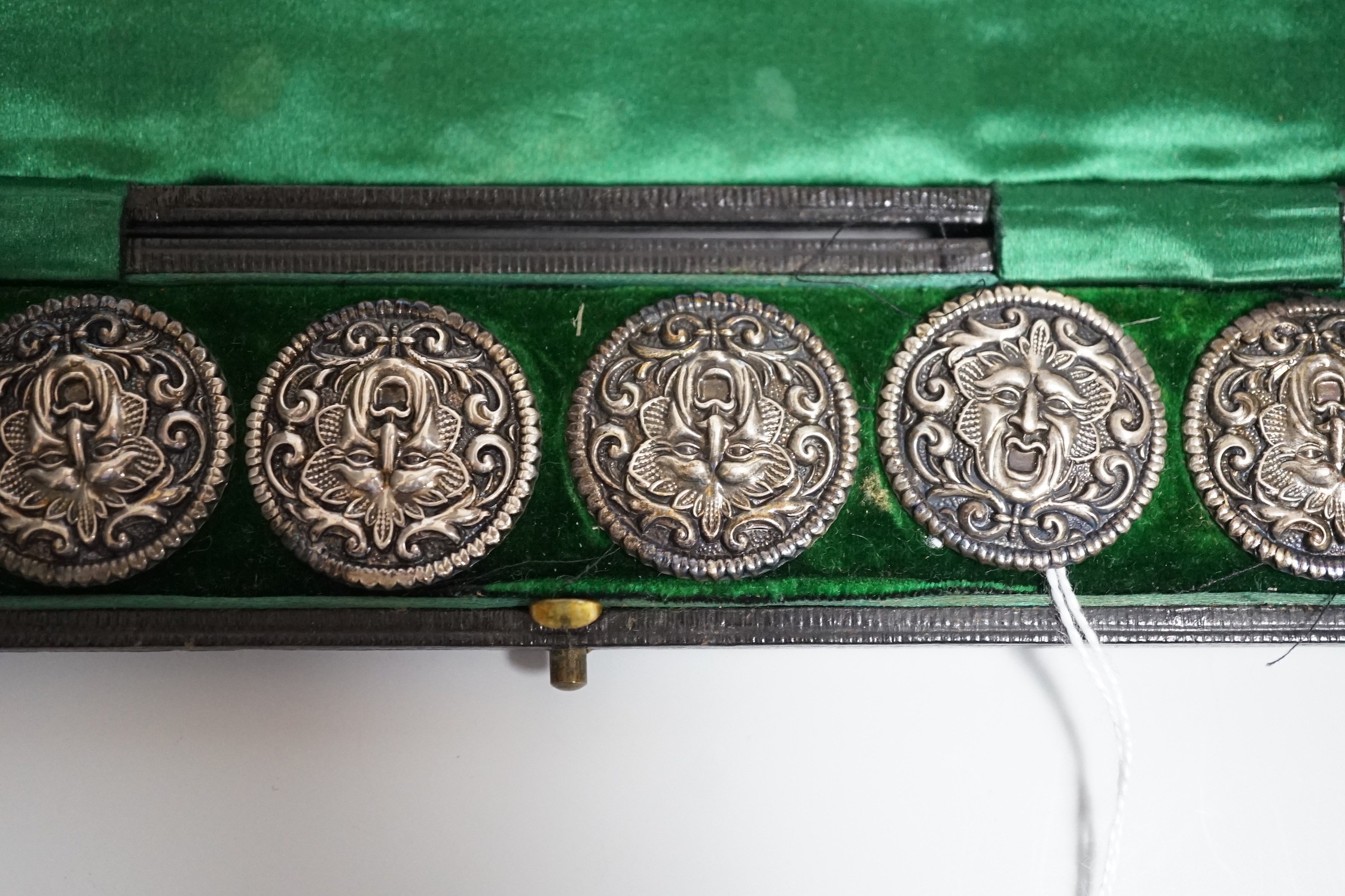 A cased set of six Edwardian silver buttons, each embossed with a mask, Henry Matthews, Birmingham, 1902, 27mm.